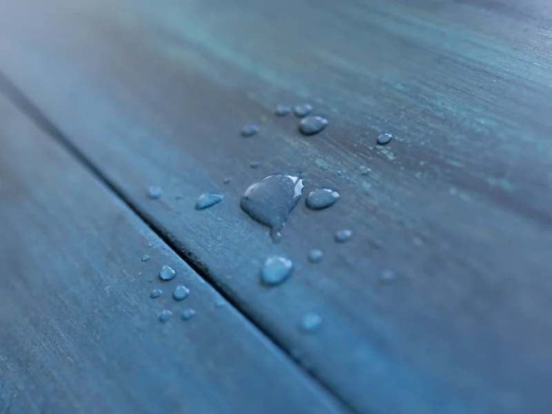 Water droplets beading on a blue waterproof wood-look plank floor