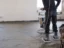 Construction worker leveling a wet concrete slab with a power float before new flooring goes down